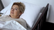 Worried elderly patient lying in sickbed and looking around, alzheimers disease