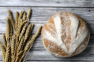 homemade bread top view with ears of wheat on a wooden table.