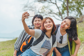 technology, travel, tourism, jungle hike and people concept - group of smiling friends with backpacks taking selfie by smartphone over venice beach background