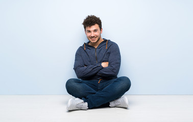 Young man sitting on the floor keeping the arms crossed in frontal position