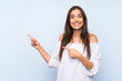 © luismolinero - Young woman over isolated blue background pointing finger to the side