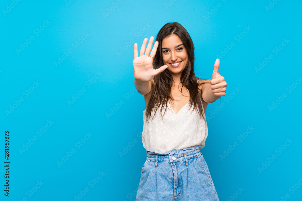 Young woman over isolated blue background counting six with fingers - obrazy, fototapety, plakaty 