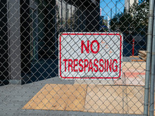 No Trespassing Sign Behind Chain Link Fence Blocking Off Urban Construction Zone