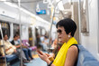© ChenPG - woman using smartphone at the MRT carriage