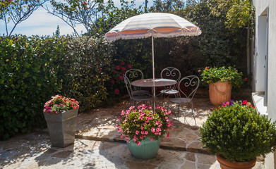 Flowered terrace with garden furniture in wrought iron and sunshade