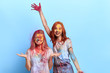 © alfa27 - ginger and blonde girls playing with colorful powder.women's faces and hair drenched in colour and in almost unidentifiable state. isolated blue background, studio shot. copy space