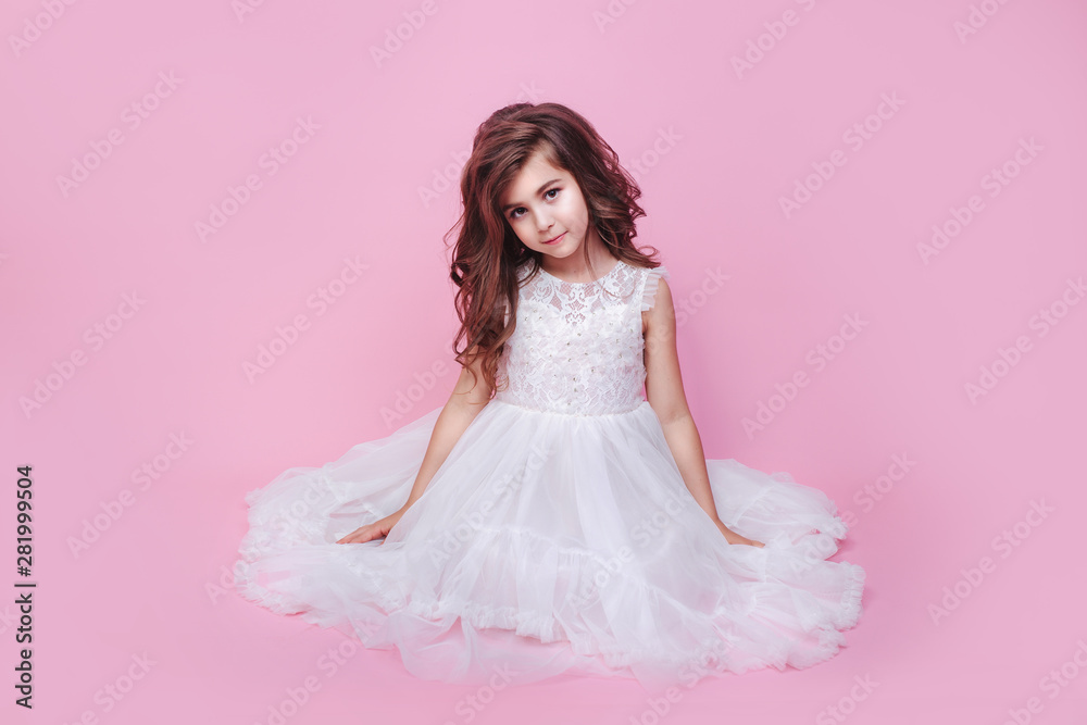 cute smiling little girl in princess dress sitting on pink background ...