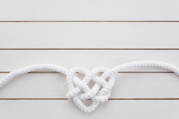 Wall Mural - Heart shaped knot on white wooden background