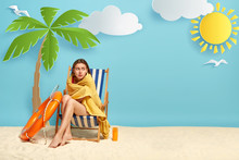 Lovely Woman Feels Cold After Swimming In Sea, Sits At Deck Chair Near Palm Tree, Wrapped In Towel, Looks Away, Afraids On Being Alone At Beach, Spends Summer Holiday At Coastline. Rest Concept