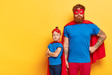 Photo Of Serious Bearded Man And Self Confident Little Child Stands Near With Crossed Arms, Wears Superhero Costumes, Show Courage, Put Their Life To Risk, Posses Brave Deeds And Noble Qualities