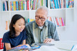 © Creativa Images - Old man teaching his granddaughter to read a book