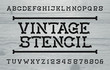 © epifantsev - Vintage stencil alphabet font. Retro letters and numbers. Distressed wood background. Vector typeface for your typography design.