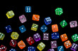 many falling translucent  multicolored  dices with white dots on black background
