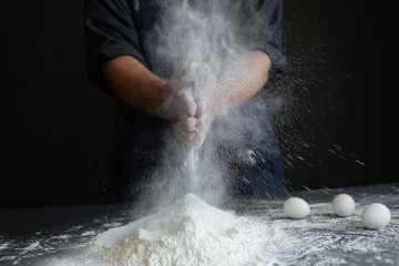 Chef claps and white flour on a black background,