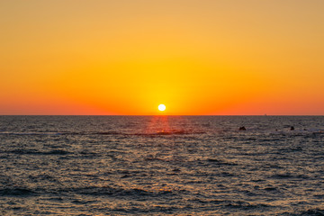 Wall Mural - idyllic peaceful natural background scenic landscape photography of vivid orange sunset above Caribbean sea wavy water surface with small ship on horizon, copy space  