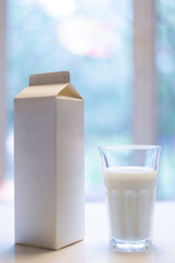 Carton box and glass of milk on table in kitchen