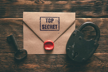 top secret documents in envelope, rusty padlock and a key on a wooden table flat lay background. con