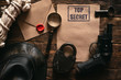 Top secret information mockup, leather hat, weapon, magnifying glass and rope on a wooden table of secret service agent flat lay background.
