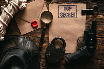 Wall Mural - top secret information mockup, leather hat, weapon, magnifying glass and rope on a wooden table of s