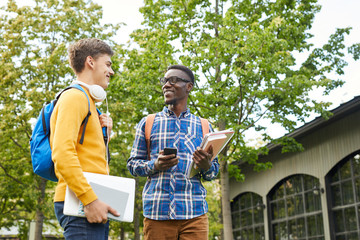 Wall Mural - Portrait of African-American student talking to friend while walking outdoors in college campus, copy space