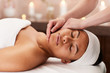 © Seventyfour - Portrait of young mixed-race woman enjoying face massage in luxury spa, copy space