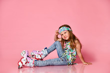 Little Baby Blond Hair Child Sitting With Roller Skates In A White Shirt And Hairband Happy Smile On A Pink Studio Background
