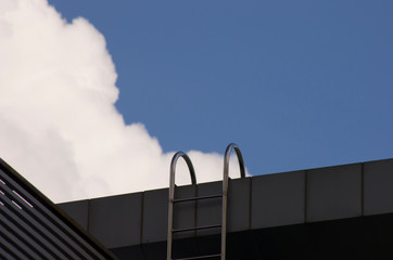 ladder to building top under blue sky and clouds