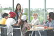 © ChayTee - Young attractive asian creative hipster female leader standing at modern office happy talking and brainstorming idea presentation with teamwork. Casual asian people business meeting workshop concept.