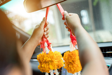 Woman flower garland in hand and praying in the new car for lucky, safety in Thai style