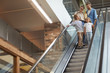 © Seventyfour - Portrait of contemporary family with two kids going down escalator in shopping mall, copy space
