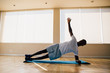 © twinsterphoto - Athletic African American man balancing on one arm while doing side plank exercise on mat in gym