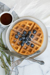 Wall Mural - Belgian Waffle with Blueberries and Maple Syrup, Dusted with Powdered Sugar, Flay Lay on Marble Background, Copy Space