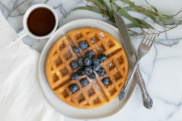 Wall Mural - Belgian Waffle with Blueberries and Maple Syrup, Dusted with Powdered Sugar, Flay Lay on Marble Background, Copy Space