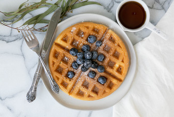 Wall Mural - Belgian Waffle with Blueberries and Maple Syrup, Dusted with Powdered Sugar, Flay Lay on Marble Background, Copy Space