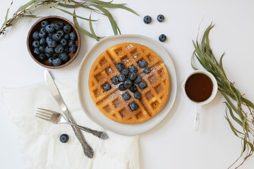 Wall Mural - Belgian Waffle with Blueberries and Maple Syrup, Dusted with Powdered Sugar, Flay Lay on White Background, Copy Space