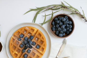 Wall Mural - Belgian Waffle with Blueberries and Maple Syrup, Dusted with Powdered Sugar, Flay Lay on White Background, Copy Space