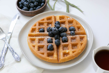 Wall Mural - Belgian Waffle with Blueberries and Maple Syrup, Dusted with Powdered Sugar, Flay Lay on White Background, Copy Space
