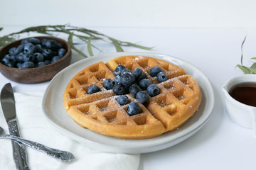 Wall Mural - Belgian Waffle with Blueberries and Maple Syrup, Dusted with Powdered Sugar, Flay Lay on White Background, Copy Space