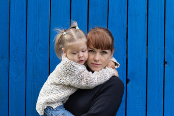 middle aged woman holding child on hands on blue wooden background