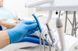 © stock28studio - Close-up hand of dentist in the glove holds dental high speed turbine. The patient in blue chair at the background. Office where dentist conducts inspection and concludes.