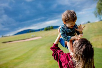 Wall Mural - mother have a fun with a son on a meadow in mountains