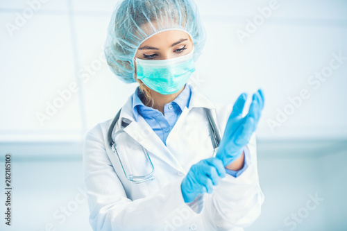 Fotomural Doctor woman surgeon specialist in sterile clothing putting on surgical gloves