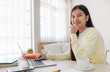 © weedezign - Asian female freelancer reading report on laptop and jot down note on table in bedroom at home.Work at home concept.work from home.relax lifestyle