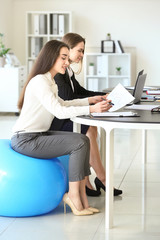 Sticker - Young businesswomen sitting on fitballs while working in office