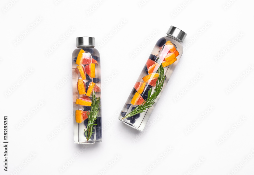 Bottles of tasty infused water on white background