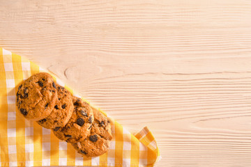 Tasty cookies with chocolate chips on light wooden background