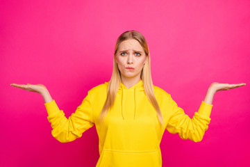 Pretty lady biting lips not sure what to buy wear yellow hoodie pullover isolated pink background