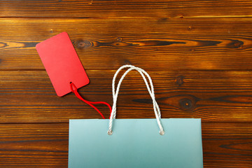 Paper bag on wooden  background with sale tag .  Mockup for design