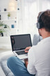 © astrosystem - Man listening to music and using laptop in the living room.