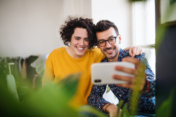 Wall Mural - Two young friends with smartphone indoors, taking selfie.